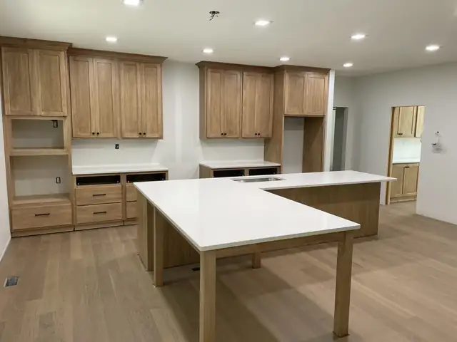 Natural wood shaker cabinets with an L-shaped white island on wood legs