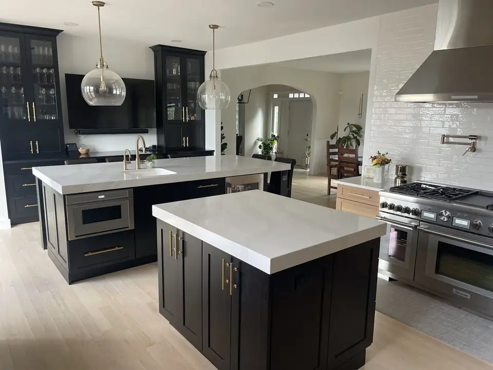 Kitchen cabinets in Defiance: espresso shaker cabinets, two islands with thick white tops, brass pulls and a white tile wall