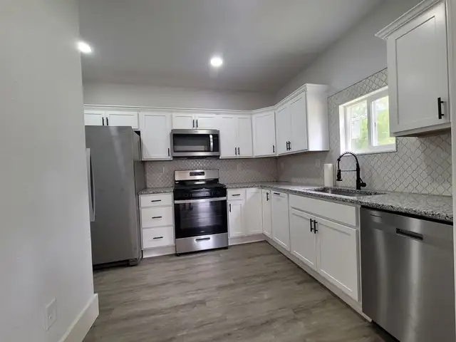 White cabinets with gray countertops, stainless appliances and wood-look floor