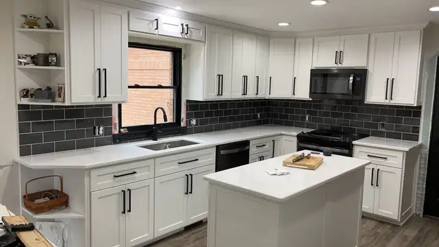 White shaker cabinets, white countertops, black subway tile backsplash and island with black hardware