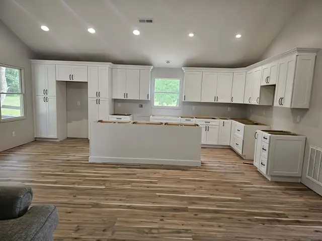 White shaker kitchen cabinets installed around a vaulted room with an island base, ready for countertops